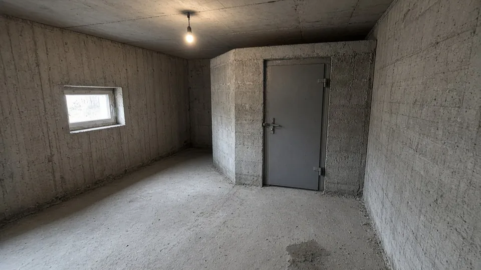 Reinforced concrete shelter room with a steel door in a home basement