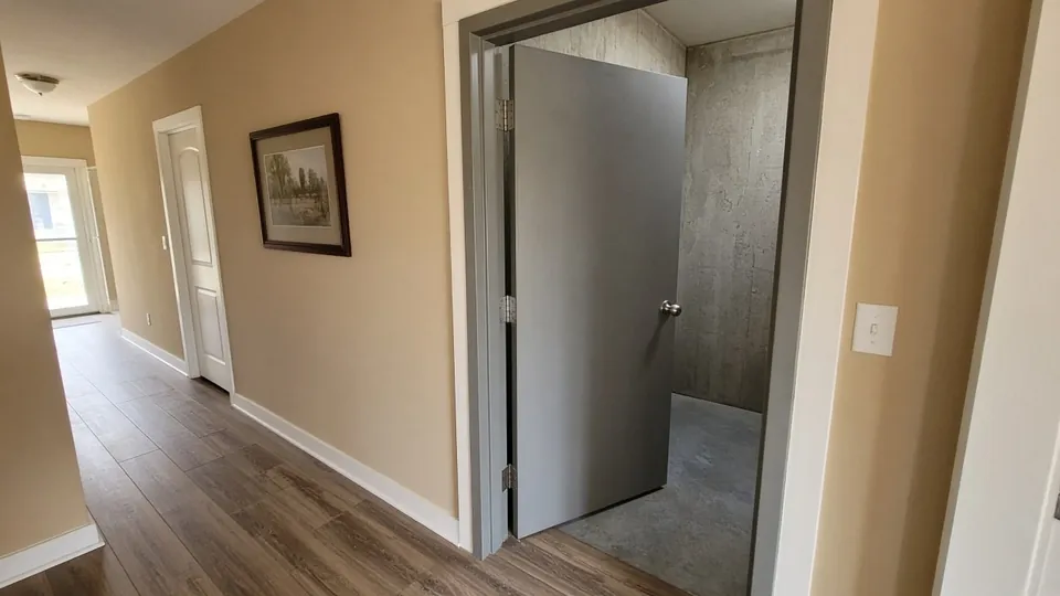 Interior tornado safe room with a heavy steel door inside a home